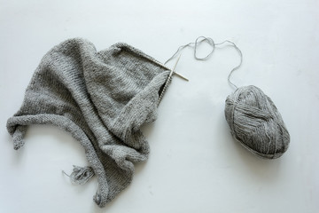 Girl knits gray sweater knitting needles on gray wooden background. Process of knitting. Top view. Flay lay