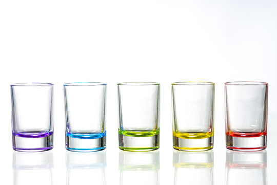 Five Multicolored Empty Shot Glasses Placed Symmetrically On A White Background