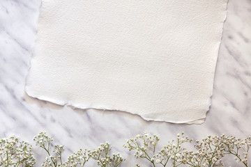 Creamy handmade paper on a marble table with white flowers