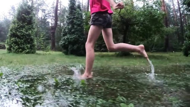 young girl in slow motion runs in a puddle