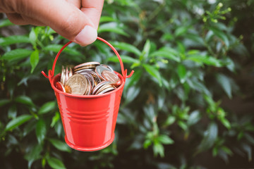 Hand holding stack coins in red bucket using as business and financial concept © jaturonoofer