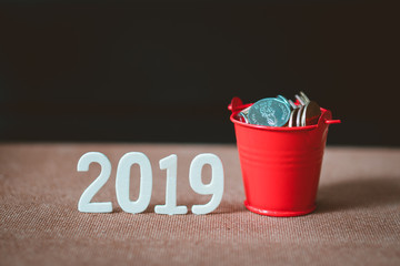 Stack coins in red bucket with year 2019 using as business and financial concept