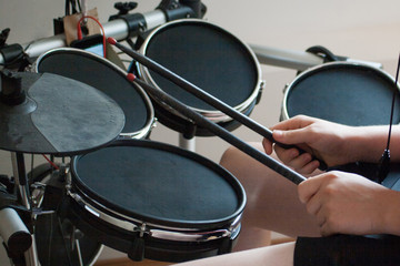 unrecognized boy playing electronic drums with black drumsticks