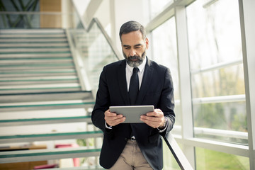 Fototapeta premium Handsome senior businessman with digital tablet in the modren office