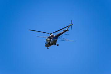 Fototapeta na wymiar A helicopter of agricultural aviation is flying in the blue sky.