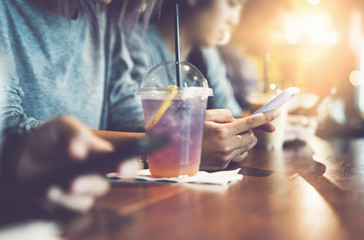 Group of woman sitting enjoy online social connection through mobile smart phone in coffee cafe