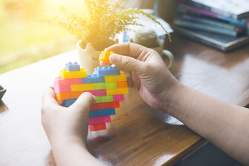 People are playing on a rainbow heart Blocks toys on the table. In vintage style.
