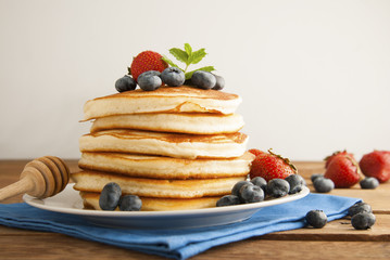 Pancakes with strawberry and blueberry jam, delicious dessert for breakfast, rustic style, wooden background.