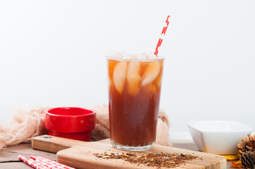Glass of iced tea with ice cubes and a paper straw