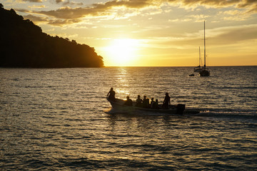 Naklejka na ściany i meble koh kood beach thailand, sunset boat orange sky people on boat, kayaking silhouette