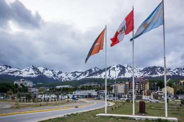 Ushuaia waterfront, with Argentina flag and snowy mountains.