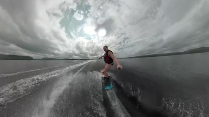Extreme sports wakeboard athlete female ripping around a lake behind a boat