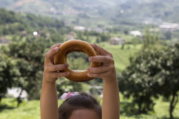 child hold the regional bagels on the green view for healthy concept.