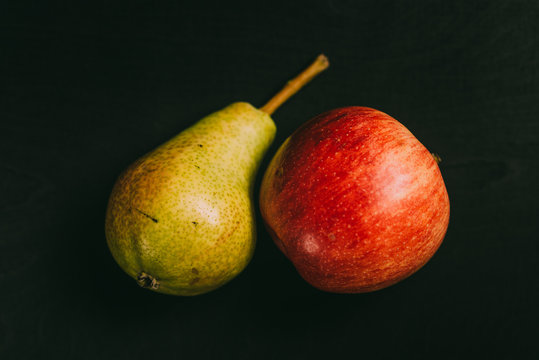 Pear and apple lying on black table in background with blank space as flat lay