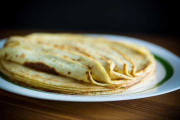 Thin pancakes stacked on a plate in a pile