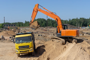 Obraz premium Excavator at the construction site will load the truck with sand