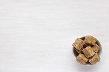 Brown sugar cane in a plate on a light background. Copy space for text.