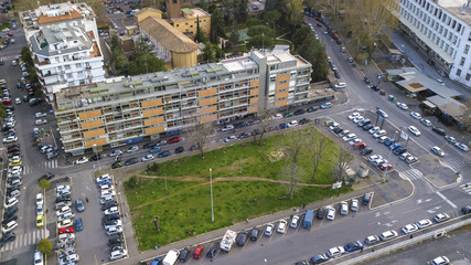 Naklejka premium Aerial view on a small square on the outskirts of a city. In the middle of the square, trees, greenery and parking cars.