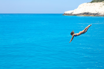 Beautiful young woman jumping into the ocean