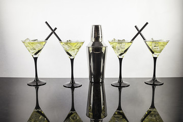Four cocktails and cocktail shaker aligned