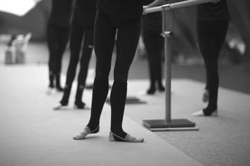 Legs of gymnasts in choreographic positions in the rehearsal room during training