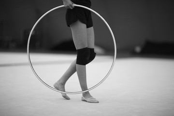 Athlete with a hoop for an exercise in rhythmic gymnastics in a training hall