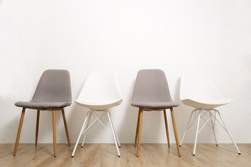 Multiple white gray elegant loft style empty chairs standing in room, wooden floor & big blank wall background with a lot of copy space for text. Vacant seats. Human resources hiring campaign concept