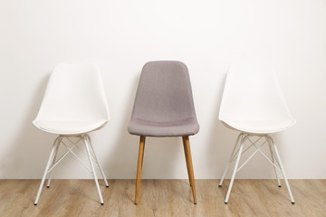 Multiple white gray elegant loft style empty chairs standing in room, wooden floor & big blank wall background with a lot of copy space for text. Vacant seats. Human resources hiring campaign concept