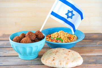 Israel flag, Falafel balls in a bowl, pita bread and hummus topped chickpea seeds in a dish on...