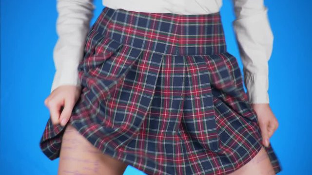 Midsection of teenage girl, cheat sheet written on hips hidden under a skirt. 4k, close-up, blue background, slow-motion shooting.