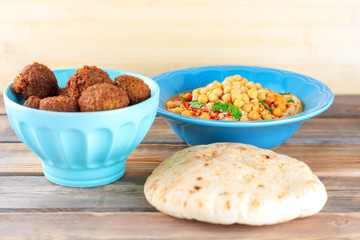 Falafel balls in a bowl, pita bread and hummus topped chickpea seeds in a dish on wooden  background. Falafel,hummus and pita Traditional Middle Eastern healthy vegan food.