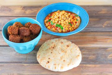 Falafel balls in a bowl, pita bread and hummus topped chickpea seeds in a dish on wooden  background. Falafel,hummus and pita Traditional Middle Eastern healthy vegan food.
