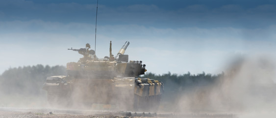 Obraz premium Military or army tank ready to attack and moving over a deserted battle field terrain. a lot of dust. copyspace