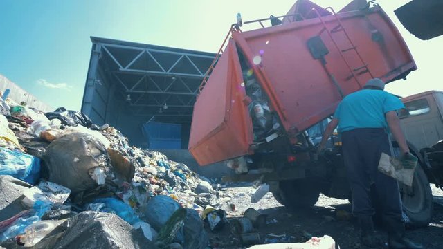 Litter is getting discarded from a truck in a scrapyard. Environmental pollution concept.
