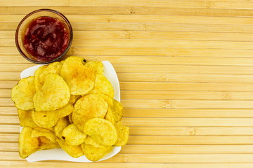 Potato chips on a plate. Wooden table. Salty food for beer