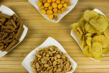Peanut, Snack, nut, potato chips  on a plate. Wooden table. Salty food for beer
