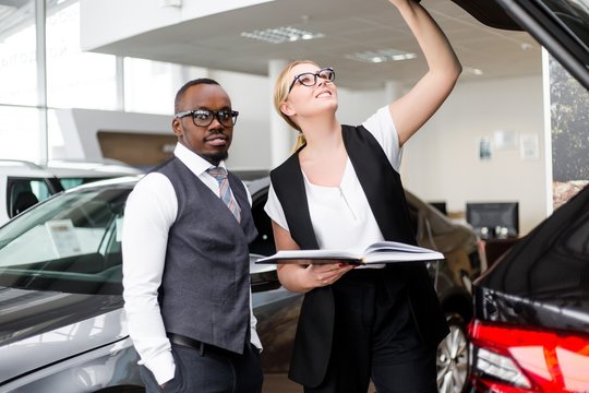 Business woman working with African man checking on a new car by opening the trunk