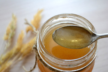 Honey in a transparent jar on the table. Spoon in a jar of honey