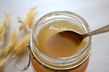 Honey in a transparent jar on the table. Spoon in a jar of honey