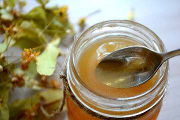 Honey in a transparent jar on the table. Spoon in a jar of honey