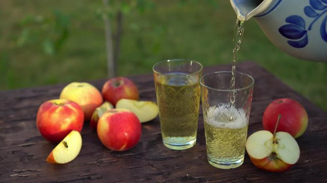 Traditional apple wine in the city of Frankfurt in Hesse. A jug of wine is on an old wooden table in the garden, around it are apples