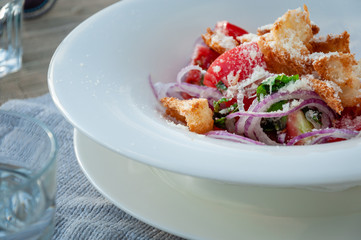 Tuscan Panzanella, traditional Italian salad with tomatoes and bread. With glass of water
