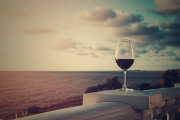 Glass of red wine on the beach at colorful sunset