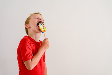 Boy with red shirt on white background eating a lollipop colorful fun and laughing.