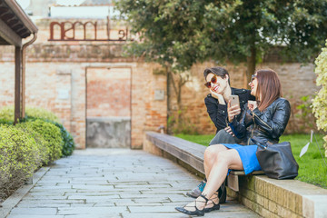 Fototapeta premium two women using smart phone in the city