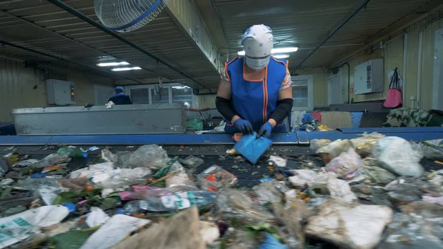 Litter is moving along the conveyor belt and getting classified by a female employee