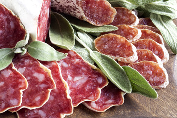 slices of French cheese-dried salami with spices on wooden background