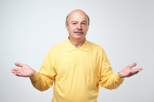 Emotional bearded man not sure for something. Studio shot, gray background