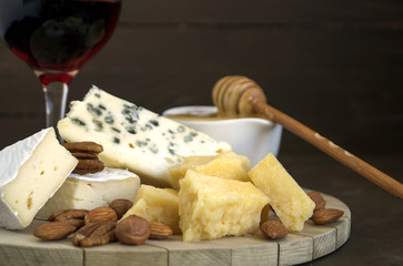 Cheese plate with nuts and honey on dark background.