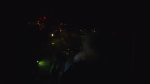 Night time house fire flashing lights and smoking roof. 